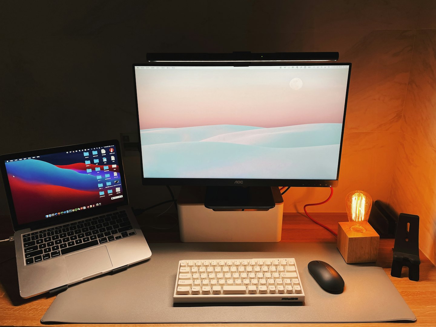 Na drewnianym biurku stoją laptop i monitor.